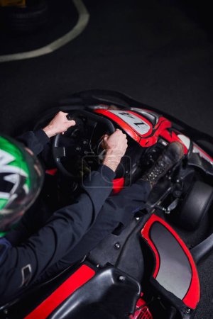 top view of man in helmet and sportswear driving go kart on indoor circuit, adrenaline concept