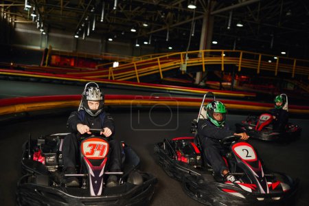 fokussierte multikulturelle Go-Kart-Rennfahrer auf Indoor-Rundkurs, Speed-Rennen und Motorsport
