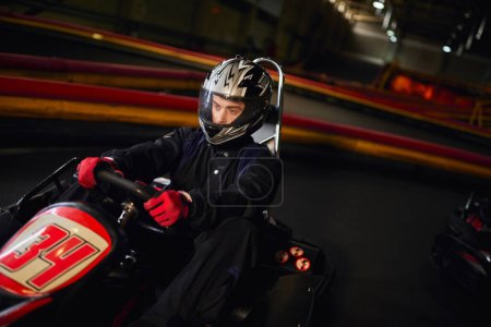 conductor enfocado en carreras de casco en coche de karting go en circuito interior, velocidad de conducción y el concepto de automovilismo