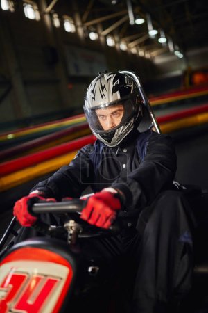 piloto concentrado en la conducción de casco ir coche de karting en circuito interior, concepto de competición de automovilismo