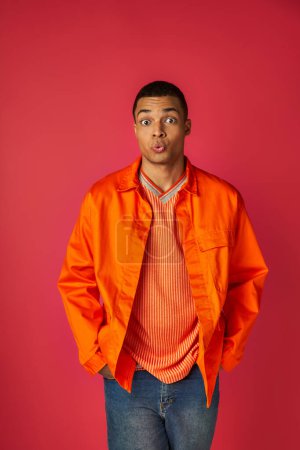 Photo for Discouraged african american man pouting lips and looking at camera on red, orange shirt, stylish - Royalty Free Image