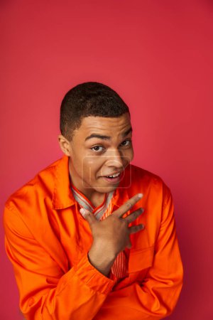 Photo for Surprised african american man pointing with hand at himself and looking at camera on red - Royalty Free Image