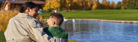 Photo for Bonding between mother and child, cheerful african american woman hugging boy, pond, swans, banner - Royalty Free Image