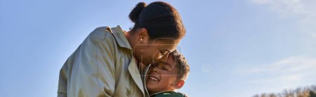 Photo for Candid, autumn season, happy african american woman in outerwear hugging cheerful son, banner - Royalty Free Image