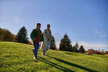 sonniger Herbsttag, fröhliche afrikanisch-amerikanische Frau läuft mit Sohn im Park, offen
