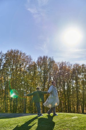 freudige Mutter mit Sohn, afrikanisch-amerikanische Frau spaziert mit Junge im Park, sonniger Tag, Herbst