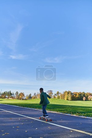 Photo for Cute boy in outerwear riding penny board, asphalt, park, fall season, kid in autumnal clothes - Royalty Free Image
