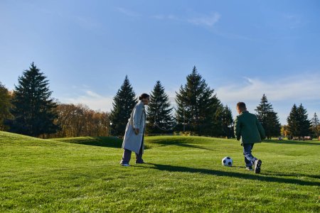 wesoły afrykański chłopiec gra w piłkę nożną ze szczęśliwą matką na zielonym polu, piłka nożna, jesień, biegać