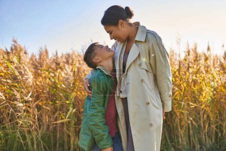 motherly love, african american mother in autumnal clothes embracing son, fall season, outerwear