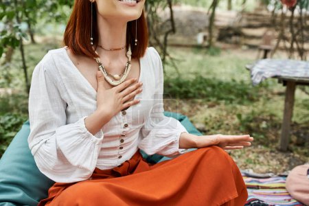 cropped view of stylish and trendy woman sitting on meadow in retreat center