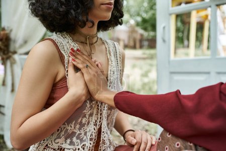 abgeschnittene Ansicht multiethnischer Frauen, die im Retreat-Zentrum Meditation im Freien praktizieren