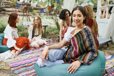 Photo for Smiling young woman in boho outfit looking at camera near multiethnic friends in retreat center - Royalty Free Image