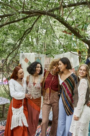 positive multiethnische Frauen in Boho-Kleidung, die sich umarmen, während sie Zeit im Retreat Center verbringen