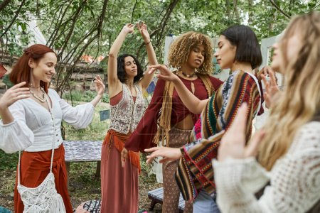 stilvolle multiethnische Freunde mit geschlossenen Augen tanzen im Freien in einem modernen Rückzugszentrum
