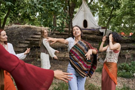 smiling woman dancing together with multiethnic friends in summer in retreat center