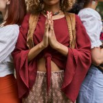 cropped view of interracial women in stylish clothes doing praying hands gesture in retreat center