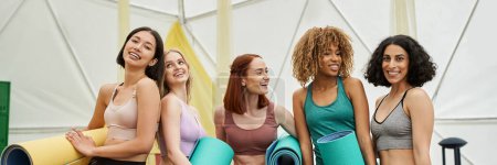 women retreat concept, multiethnic girlfriends in sportswear standing with yoga mats, banner
