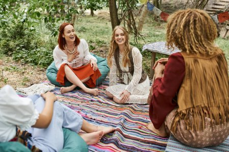 women retreat, carefree multiethnic boho style girlfriends talking on colorful blanket outdoors
