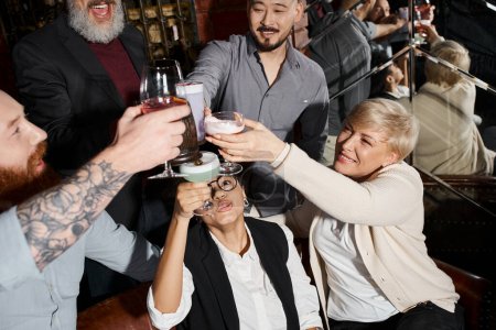 Blick aus der Vogelperspektive auf multikulturelle Arbeitskollegen, die mit alkoholischen Getränken in der Bar anstoßen, After-Work-Spaß