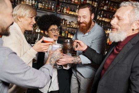 Téléchargez les photos : Heureux compagnons de travail multiethniques passer du temps après le travail dans le bar et griller avec des boissons alcoolisées - en image libre de droit