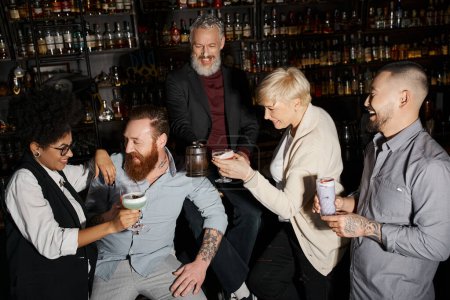 cheerful bearded man and african american woman laughing near multiethnic colleagues in bar