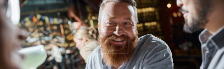 portrait de l'homme barbu gai passer après le temps de travail avec des amis multiculturels dans le bar, bannière