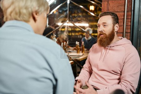 bearded tattooed men talking to middle aged woman while sharing idea of new startup project in pub