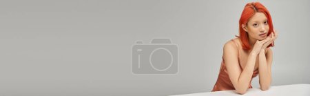 Téléchargez les photos : Captivant asiatique femme en soie rose slip robe regardant caméra sur fond gris, bannière - en image libre de droit