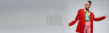 Photo for Confident african american woman in  pink glasses and vibrant attire posing on grey backdrop, banner - Royalty Free Image