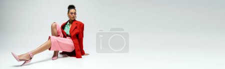 Photo for Full length of alluring african american woman in bold attire and sunglasses posing on grey, banner - Royalty Free Image