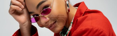 Foto de Retrato de modelo afroamericano feliz en traje elegante y gafas de sol sobre fondo gris, bandera - Imagen libre de derechos