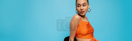 Photo for Gorgeous african american in bright outfit with hoop earrings sitting on tall chair, banner - Royalty Free Image