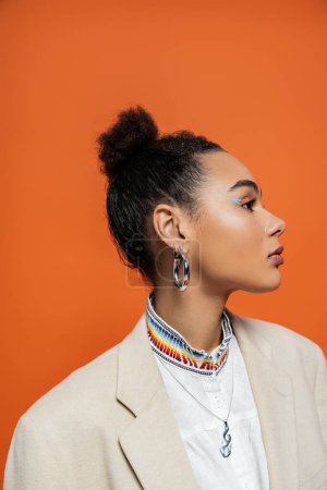 Porträt einer schönen afrikanisch-amerikanischen Frau mit Dutt und lebendigem Make-up mit Ohrringen