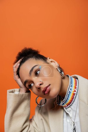 retrato de la mujer afroamericana de moda con pan de maquillaje vibrante y accesorios mirando hacia otro lado