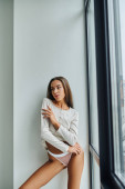 brunette young woman in long sleeve shirt and panties standing near panoramic window, sexy magic mug #674383036