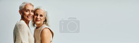 Photo for Modern senior female friends in fashionable pastel clothes smiling at camera on grey, banner - Royalty Free Image