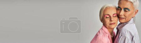 Photo for Senior lifelong female friends with silver hair and makeup standing with closed eyes on grey, banner - Royalty Free Image