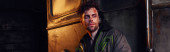 despaired man in worn jacket looking away in darkness of post-apocalyptic devastated subway, banner mug #675363866