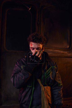 Téléchargez les photos : Homme au visage rayé portant un masque à gaz dans un environnement toxique du métro, suite à une catastrophe - en image libre de droit