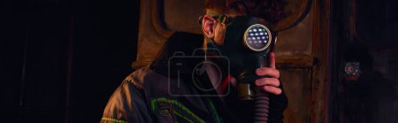 Téléchargez les photos : Homme en masque à gaz et veste usée dans un tunnel souterrain sombre, concept post-catastrophe, bannière - en image libre de droit