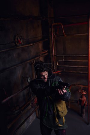 Blick aus der Vogelperspektive auf konzentrierten Mann, der mit Waffe in gefährlicher postapokalyptischer U-Bahn zielt