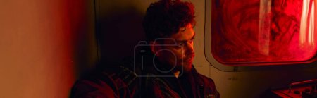 Photo for Hopeless man in abandoned subway carriage with red light and dirty window, post-apocalypse, banner - Royalty Free Image