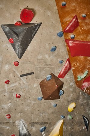vertikale Detailaufnahme einer Kletterwand mit verschieden großen Bouldern, Sport und Fitness