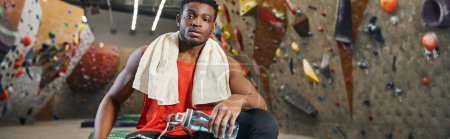 homme afro-américain athlétique sur tapis de crash avec serviette sur les épaules en regardant la caméra, bannière