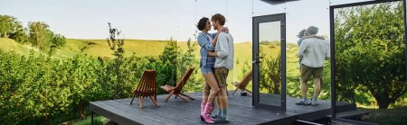 Téléchargez les photos : Couple interracial étreignant sur le porche près de la maison en verre moderne, rendez-vous romantique à la campagne, bannière - en image libre de droit