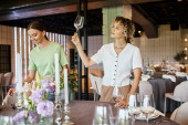 smiling woman looking at clean glass near young colleague decorating festive table in event hall Longsleeve T-shirt #675846224