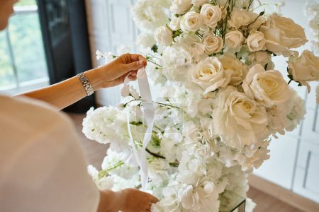 Téléchargez les photos : Vue recadrée du fleuriste avec ruban près de composition florale blanche dans la salle des événements, décoration de banquet - en image libre de droit