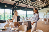 event manager with clipboard showing table with banquet setting to pleased woman in wedding venue Tank Top #675850338