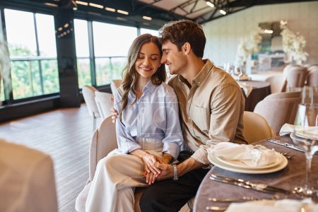 delighted couple in love smiling with closed eyes near event manager in modern wedding hall