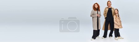 Photo for Happy redhead family in trench coats posing on grey background, three female generations, banner - Royalty Free Image